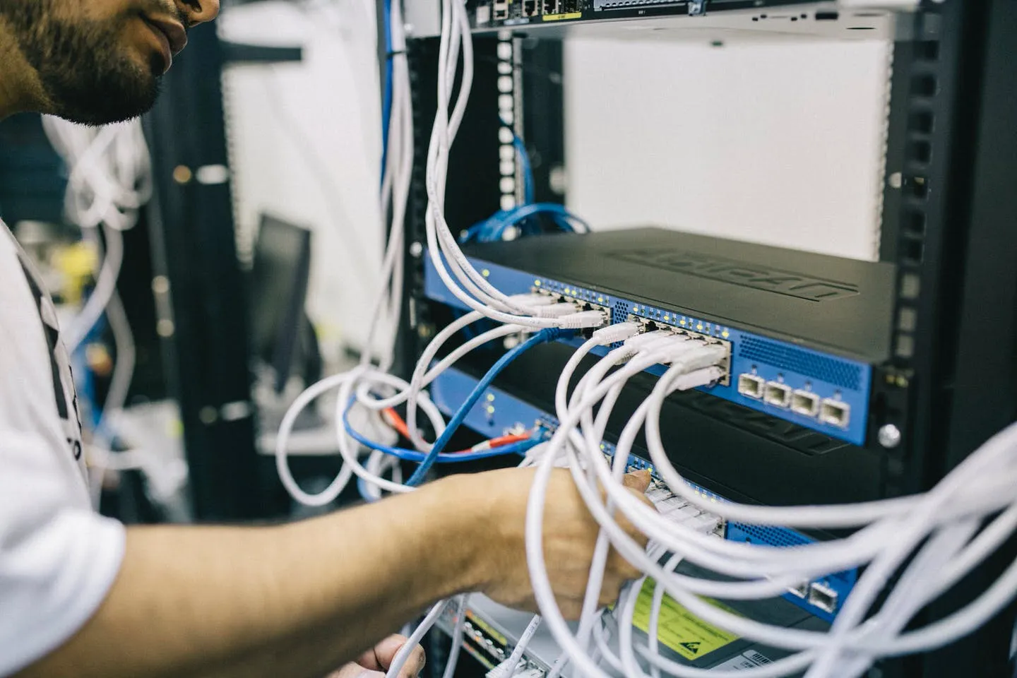 Tecnico che collega i cavi di rete a uno switch in un rack